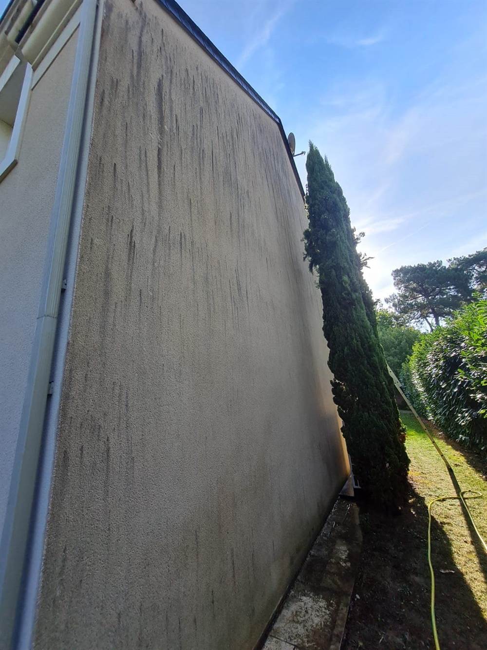 Grand mur pignon marqué par des coulures de ruissellement sur toute sa hauteur